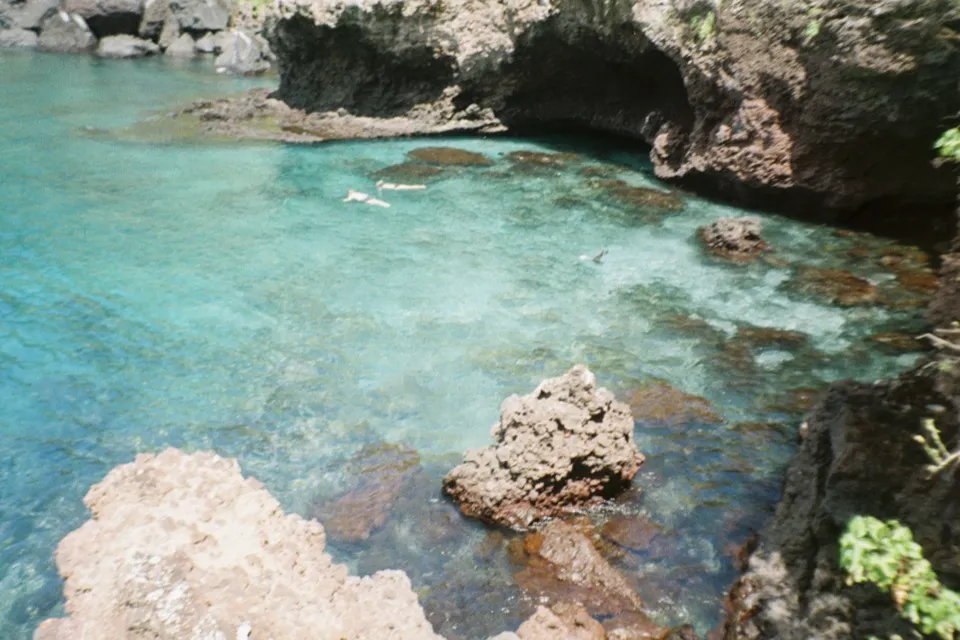 Snorkellers in the turquoise water of a rocky cove on the Galapagos coast