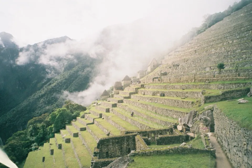 The terraces of Machu Picchu with mist pouring over the ridge